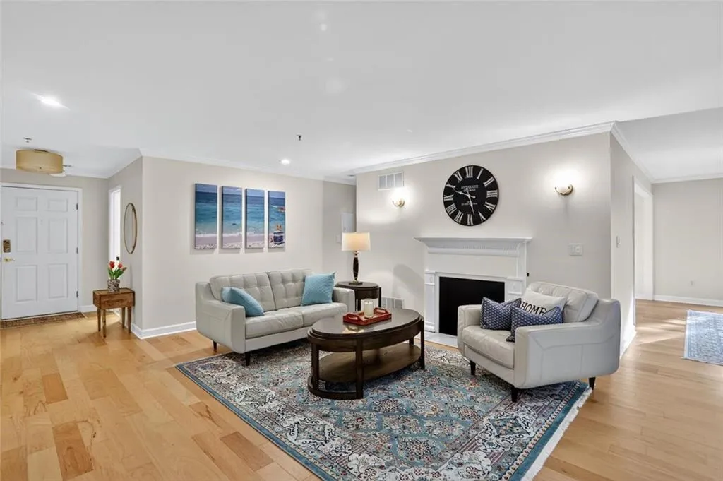 Living room featuring crown molding, light wood-type flooring, recessed lighting, and a fireplace