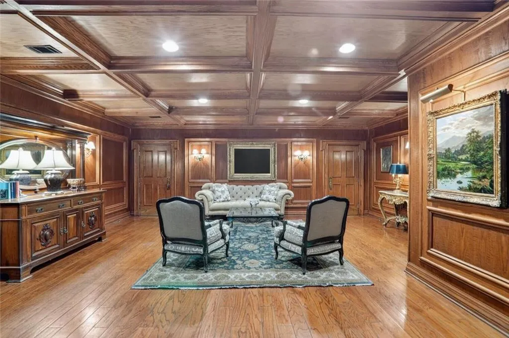 Living room with beamed ceiling, wood walls, coffered ceiling, light wood-type flooring, and crown molding