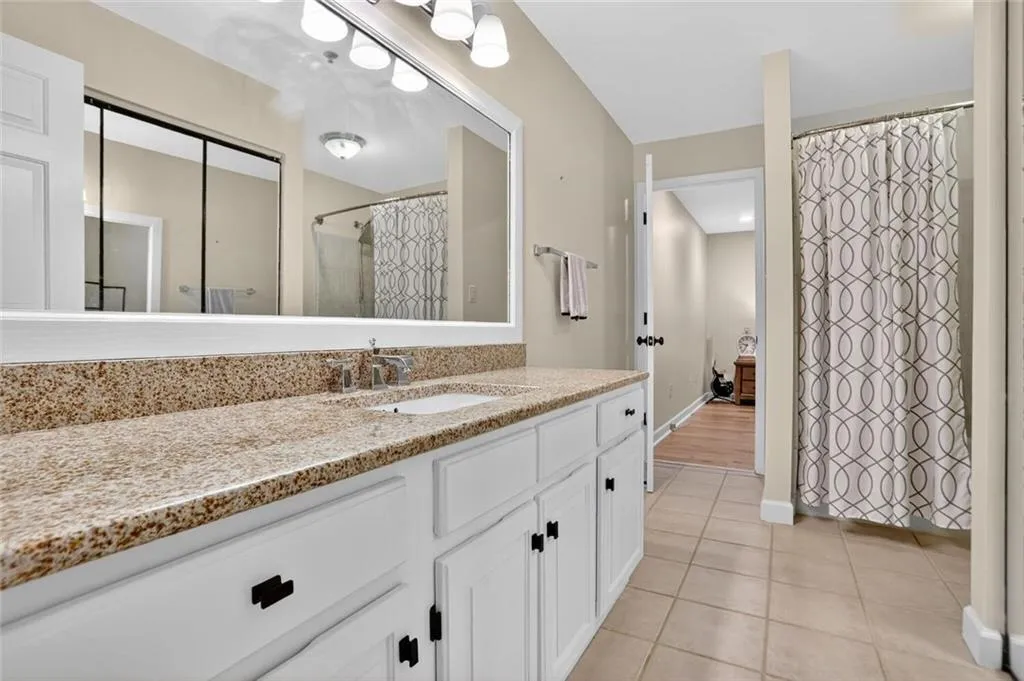 Full bathroom featuring vanity, light tile patterned flooring, and a shower with curtain
