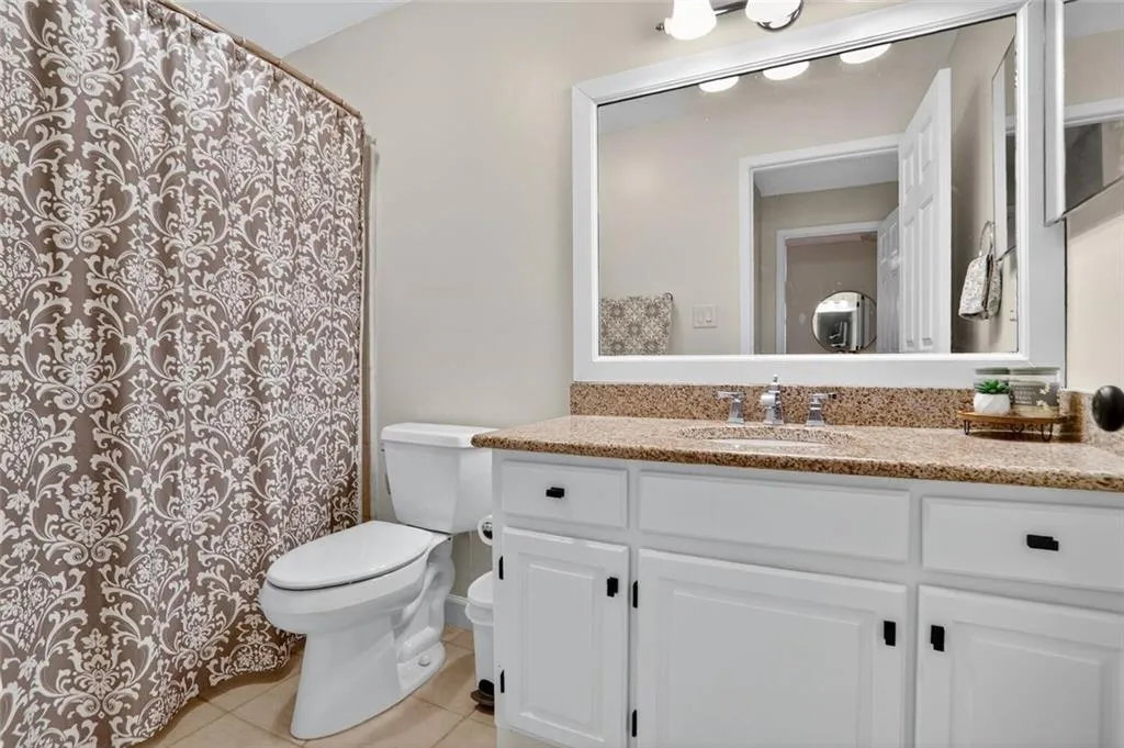 Full bath with vanity, light tile patterned floors, and a shower with curtain