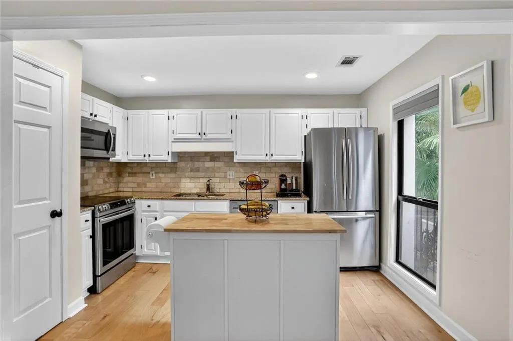 Kitchen featuring tasteful backsplash, butcher block counters, appliances with stainless steel finishes, light wood-type flooring, and recessed lighting