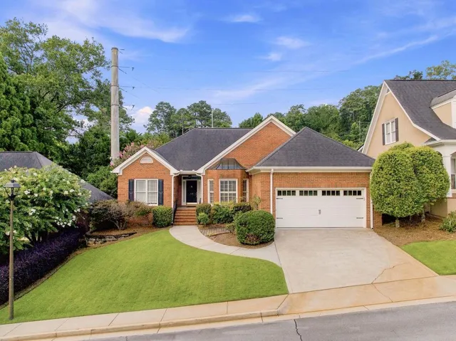 Brick facade residence featuring a two-car garage, concrete driveway, and a curved paved walkway