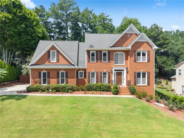 Brick exterior with multiple gables, dark shingle roof, and white window frames