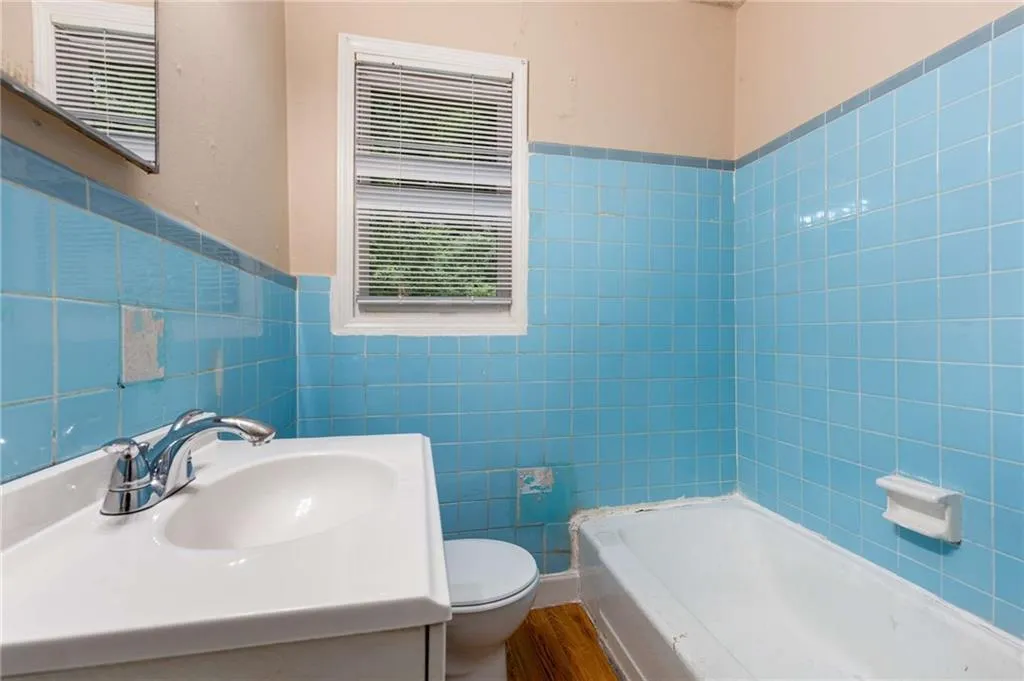 Full bath featuring vanity, tile walls, a wainscoted wall, and wood finished floors