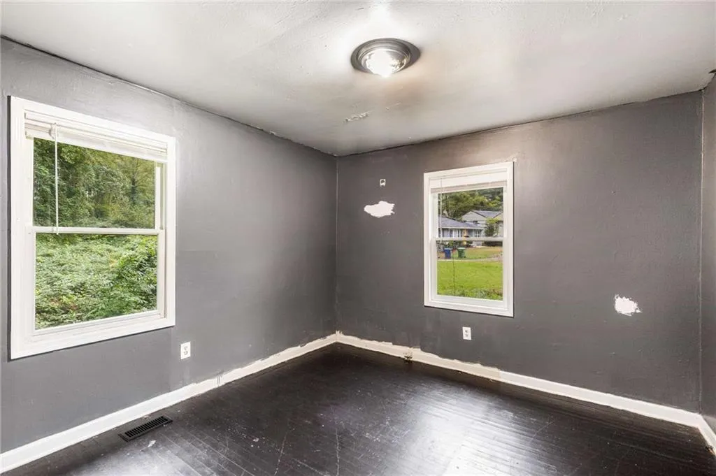Unfurnished room featuring baseboards and dark wood-style flooring