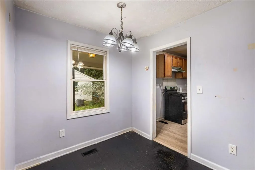 Unfurnished dining area featuring a chandelier, light wood-type flooring, and a textured ceiling