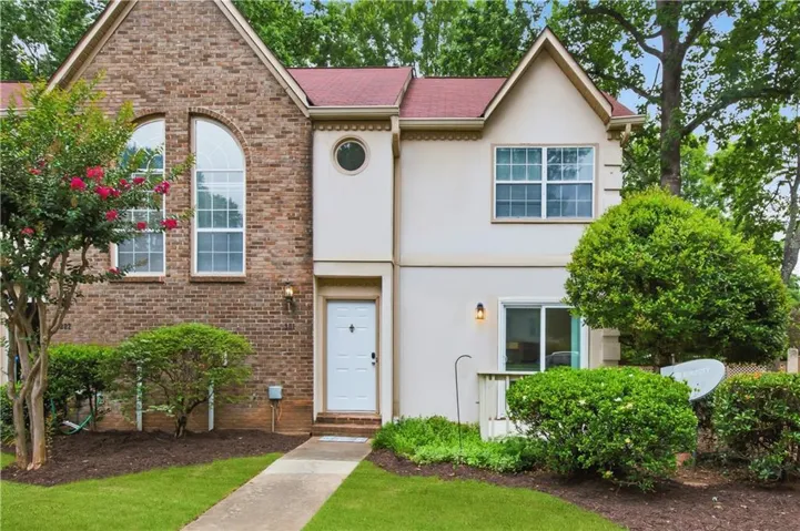 Brick and stucco exterior featuring a red roof