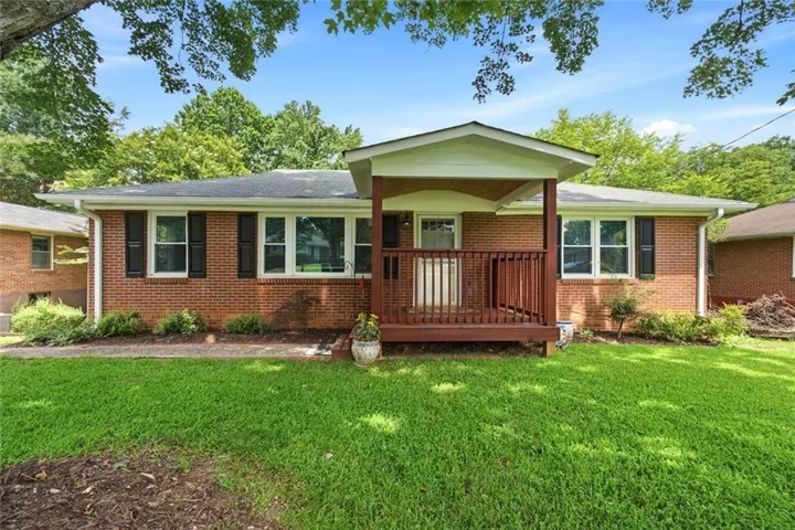 Charming all-brick ranch with a freshly stained covered front porch, black shutters, and lush landscaped front yard.