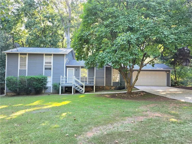Siding exterior, attached garage, mature tree, concrete driveway, and front entry deck