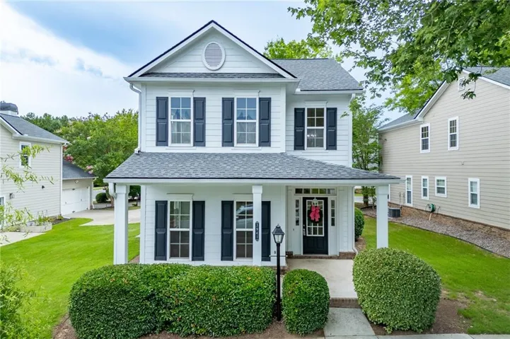 Two-story residence featuring a covered front porch with white columns, a dark front door, and dark window shutters