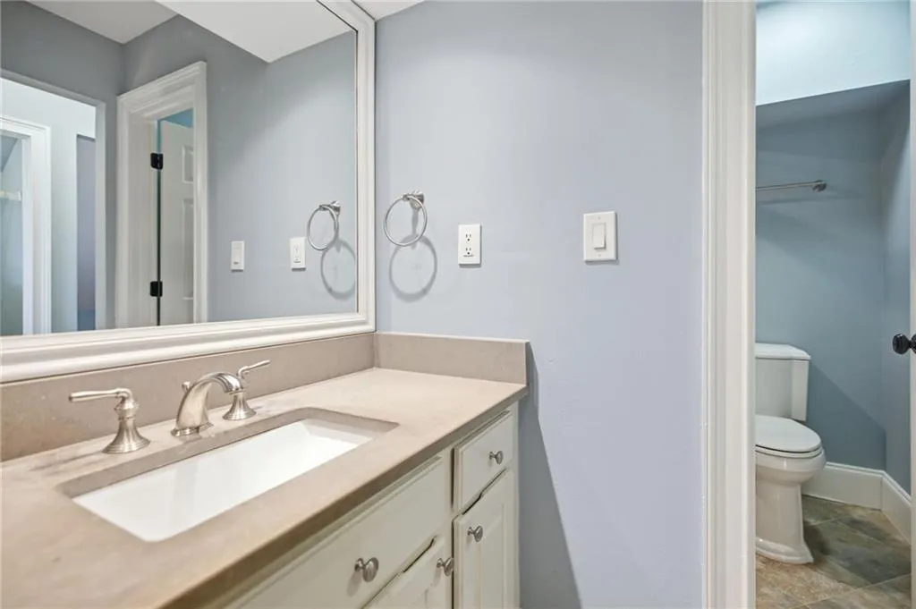 Vanity with integrated sink, brushed nickel faucet, and a large framed mirror