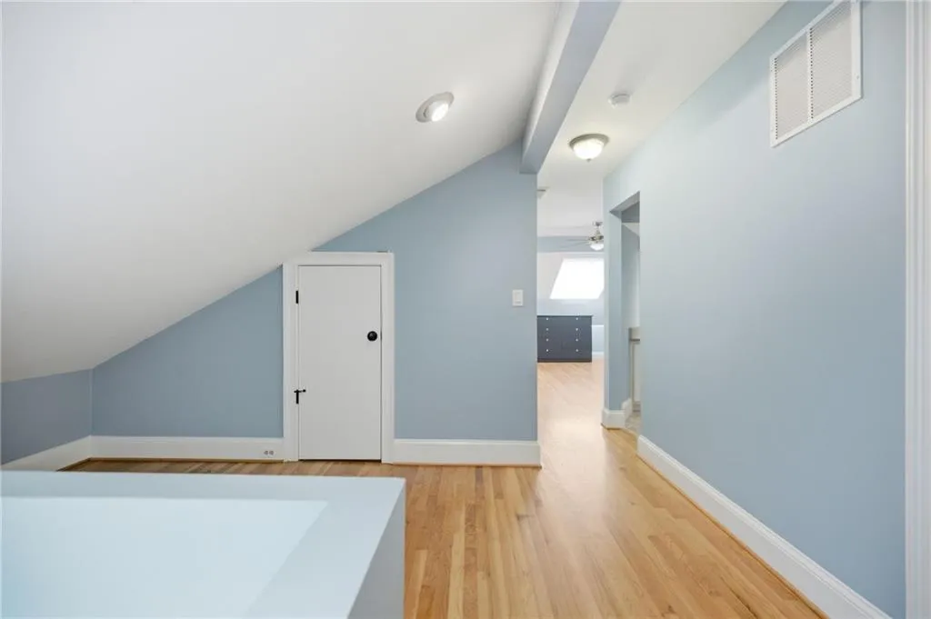 Hardwood flooring throughout, recessed lighting, white baseboards, and light blue wall tones