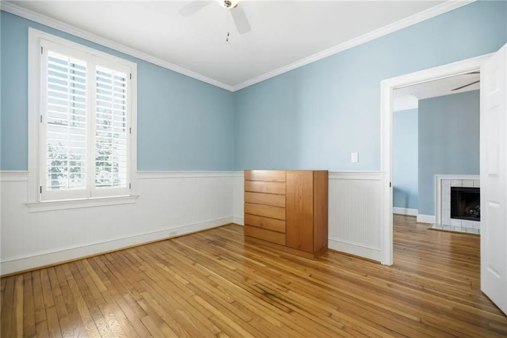Hardwood flooring, crown molding, plantation shutters, beadboard wainscoting, and a ceiling fan