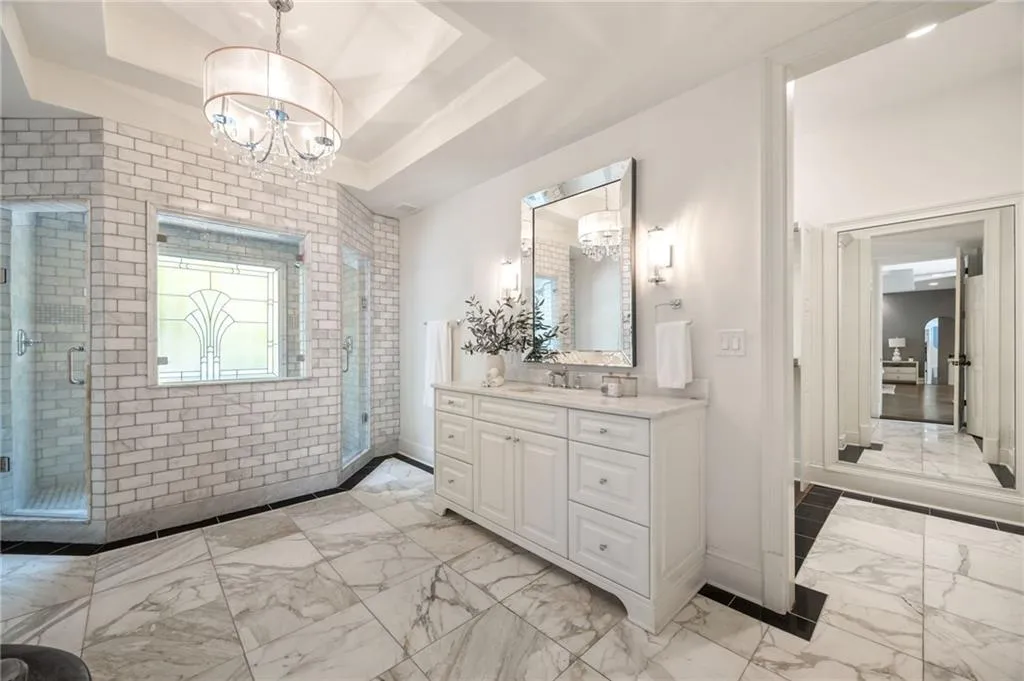 Bathroom featuring vanity, a shower stall, light marble finish flooring, and a raised ceiling