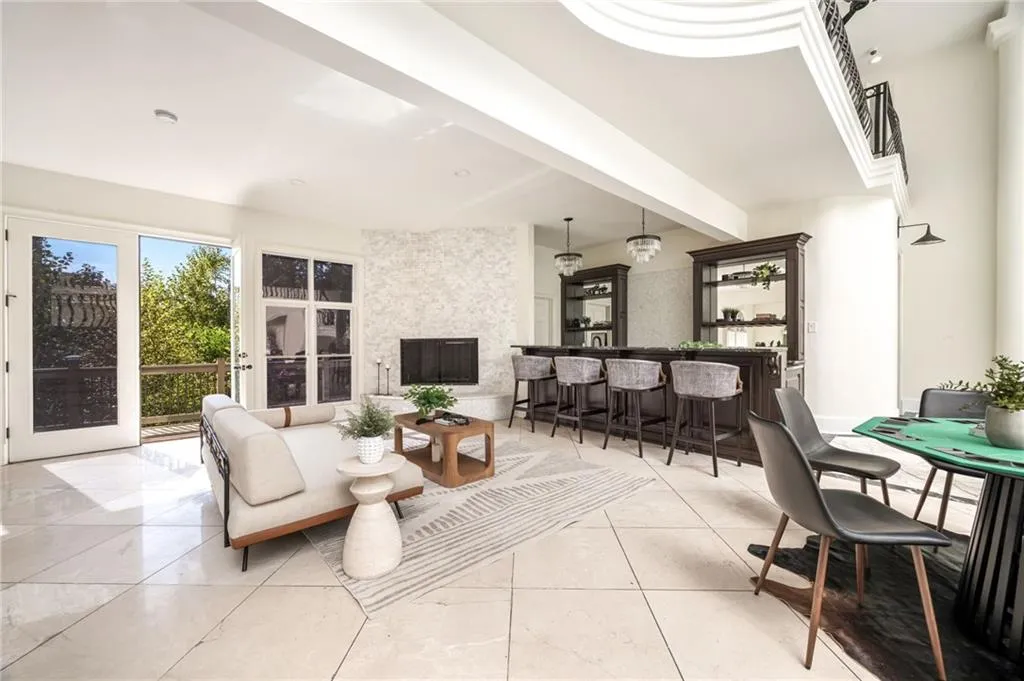 Living area with beamed ceiling, light tile patterned flooring, and bar