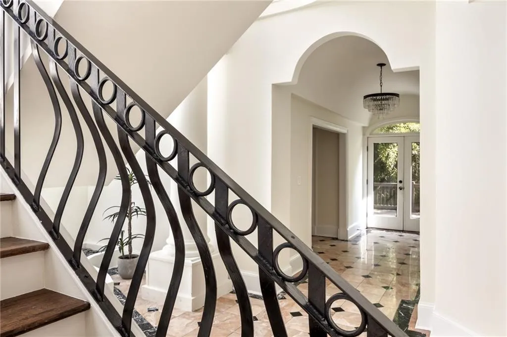 Staircase featuring french doors, tile patterned flooring, arched walkways, and a chandelier