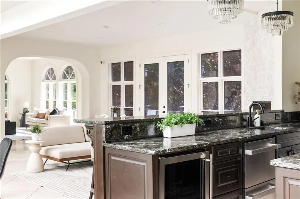 Bar featuring dark stone counters, beverage cooler, stainless steel dishwasher, light tile patterned flooring, and a chandelier