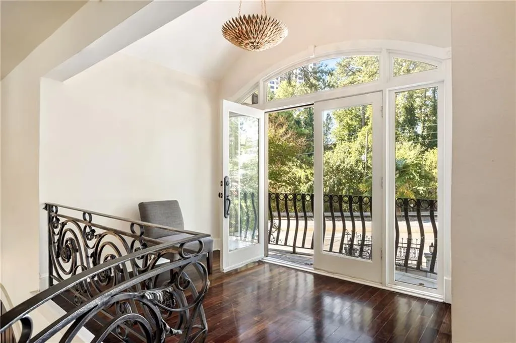 Doorway to outside with hardwood / wood-style floors, a chandelier, and vaulted ceiling