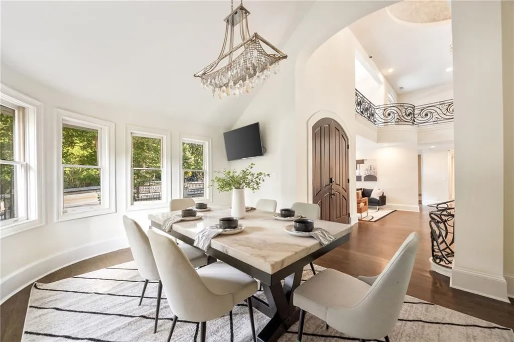 Dining area with arched walkways, a towering ceiling, dark wood-style floors, a chandelier, and recessed lighting