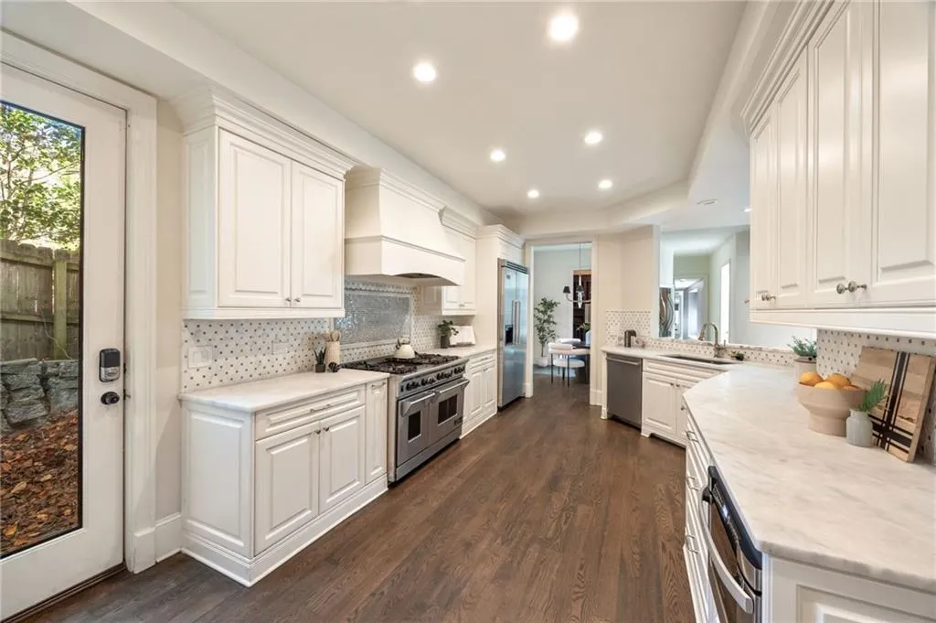 Kitchen with white cabinetry, dark wood finished floors, recessed lighting, high end appliances, and custom range hood