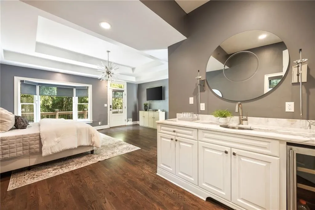 Bedroom featuring beverage cooler, a tray ceiling, dark wood-style flooring, and a chandelier