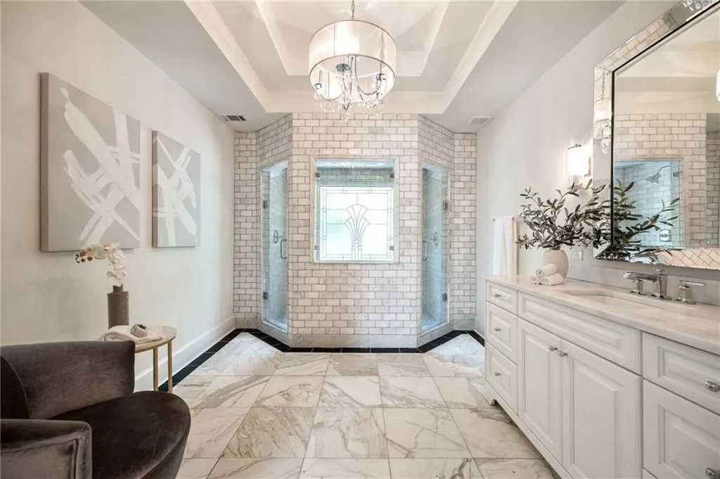 Entrance foyer featuring light marble finish flooring, a chandelier, and a raised ceiling