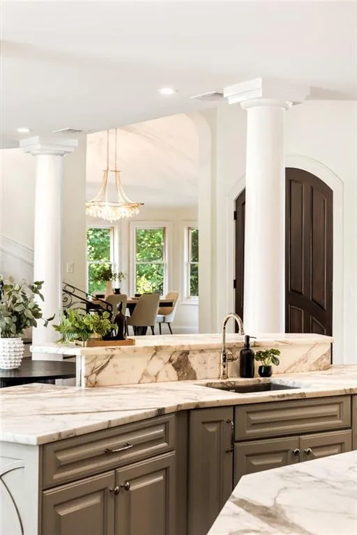 Kitchen featuring gray cabinets, light stone counters, pendant lighting, and recessed lighting