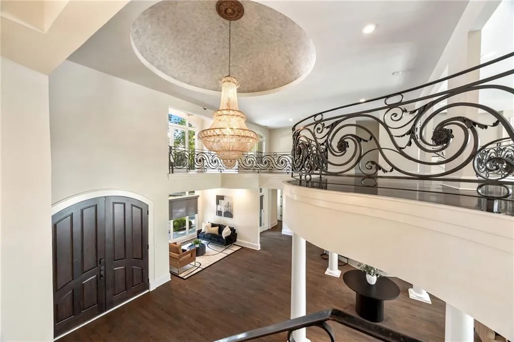 Entrance foyer with wood finished floors, recessed lighting, a raised ceiling, a high ceiling, and a chandelier