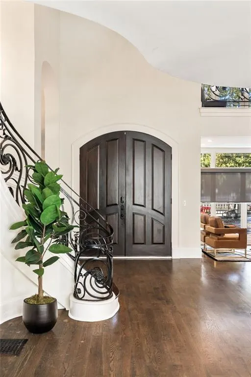 Entryway featuring dark wood-type flooring, arched walkways, and a towering ceiling