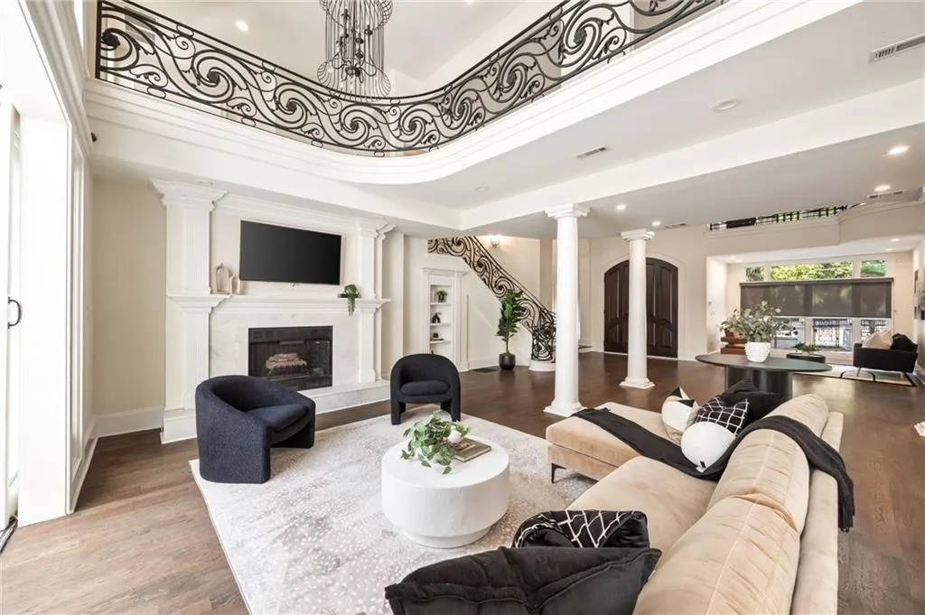 Living area with recessed lighting, a fireplace, ornate columns, wood finished floors, and a chandelier