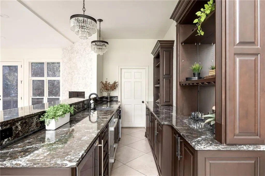 Kitchen featuring dark stone counters, dark brown cabinetry, light tile patterned flooring, and wine cooler