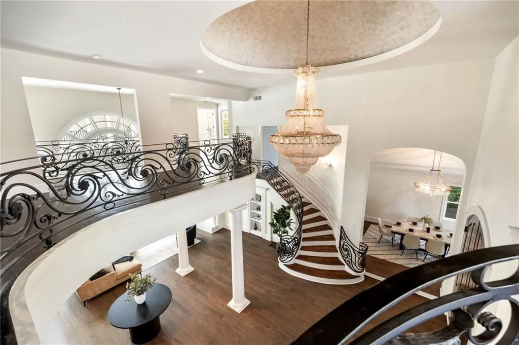 Stairs featuring a chandelier, wood finished floors, a tray ceiling, and recessed lighting