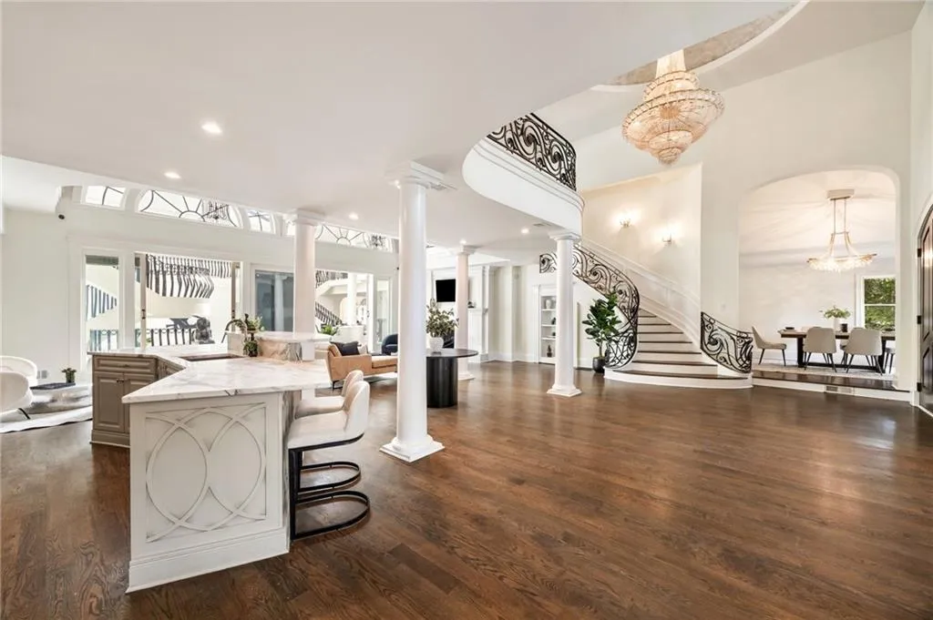 Kitchen featuring open floor plan, a breakfast bar area, light stone countertops, recessed lighting, and dark wood-type flooring