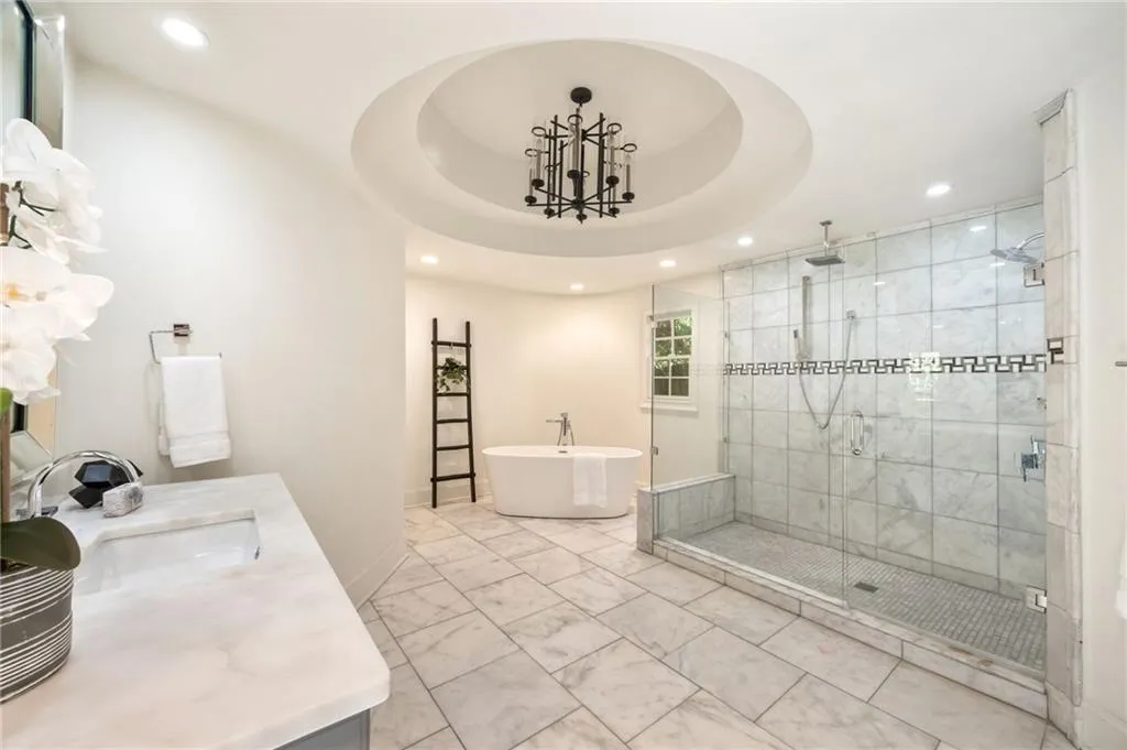 Bathroom featuring a freestanding bath, a shower stall, vanity, recessed lighting, and a raised ceiling