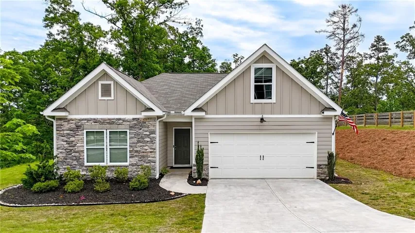 Exterior featuring mixed material siding, a front-facing garage, and mature landscaping
