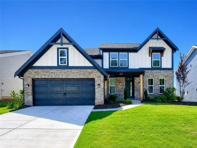 Contemporary two-story residence featuring a dark brick and white vertical siding exterior, dark blue trim, a two-car garage, and a concrete driveway