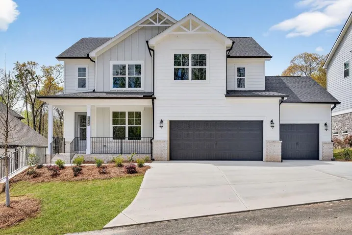 Modern inspired farmhouse featuring board and batten siding, roof with shingles, a porch, driveway, and a garage