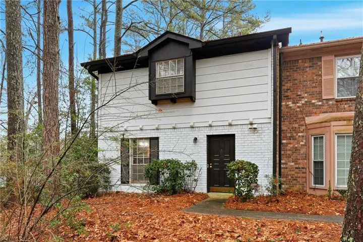 White painted brick and siding exterior with a dark front door and an upper bay window