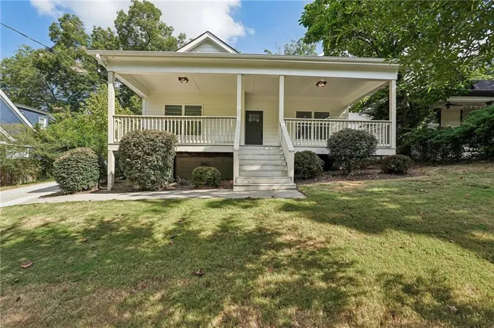 Expansive front porch with white railing, covered entry, and exterior lighting