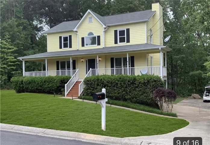 Yellow siding exterior with black shutters, a full-width covered porch, and a two-story chimney