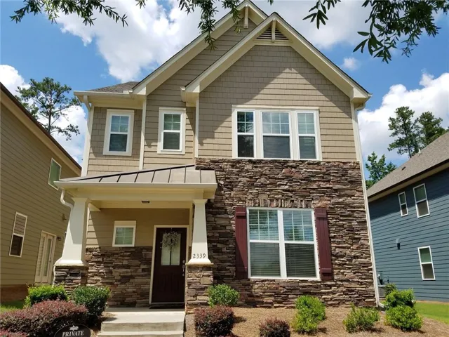 Two-story home featuring a striking mixed-material exterior with stacked stone accents on the lower facade and neutral siding above