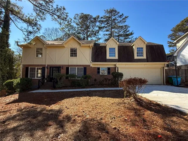 View of front of home with brick siding, concrete driveway, and roof with shingles