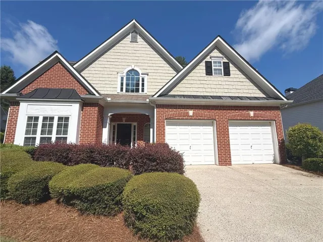 Brick and shingle exterior with a covered entry, arched window, and bay window