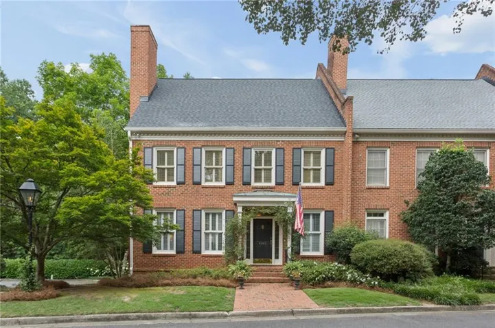Brick facade townhome with a gabled roofline and prominent brick chimneys