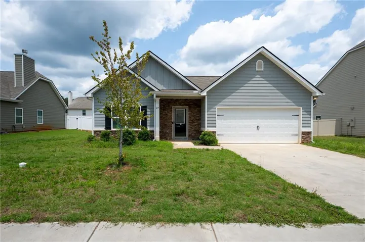 Single-story residence featuring light blue siding, stone facade accents, a two-car garage, and a concrete driveway