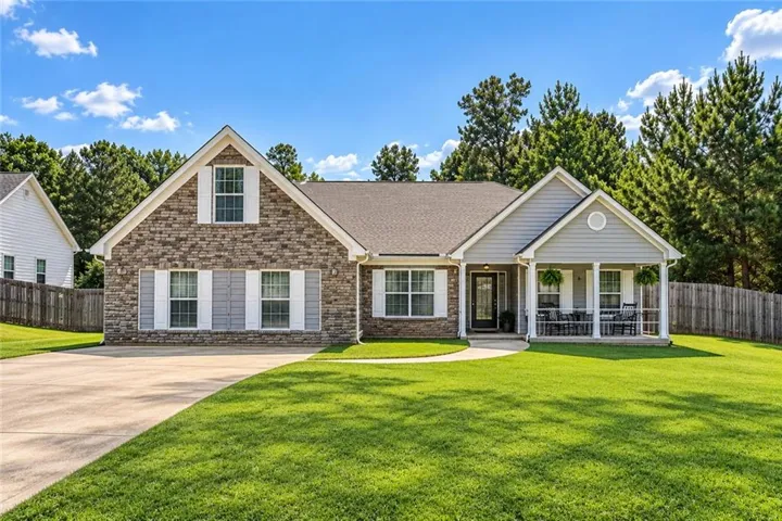 Stone and siding exterior with a covered porch, an attached front entry, and a paved driveway