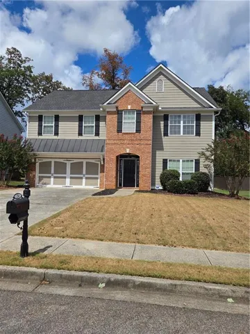 Two-story residence featuring a brick and siding exterior, an arched entryway, a two-car garage, and a paved driveway