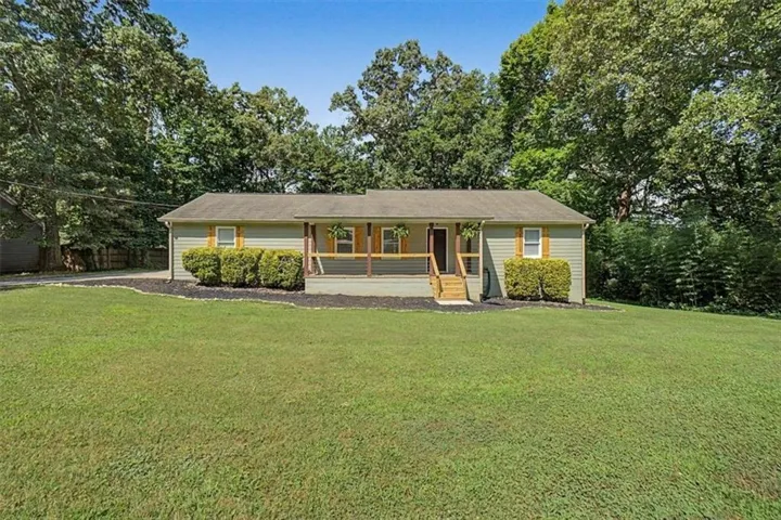 Ranch-style exterior with light green siding and a covered front porch featuring wood columns