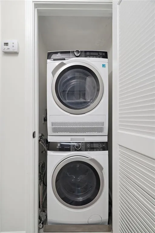 Compact laundry closet featuring a stacked washer and dryer unit