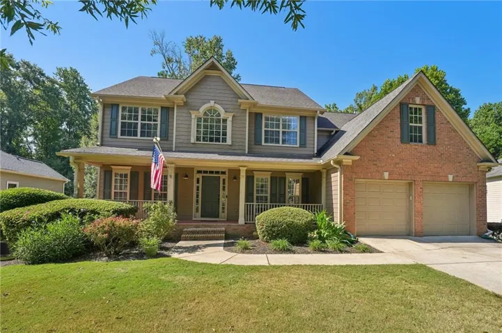 Brick and siding exterior with a two-car garage, covered front porch, and mature landscaping